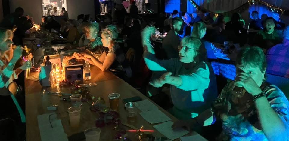 Fest Over Stevns Musikbanko 05 2026 – glade gæster i farverigt lys ved langbordet